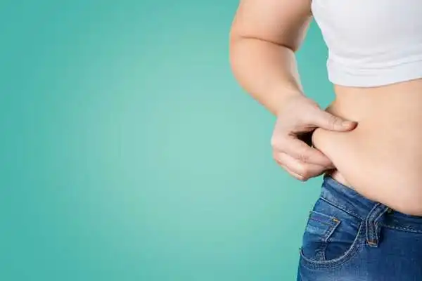 Image of woman pinching her love handles to show weight gain Uxbridge